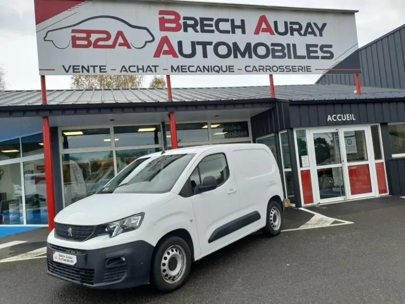 Peugeot Partner blanc en 3/4 avant droit, utilitaire compact stationné devant un garage Brech Auray Automobiles.