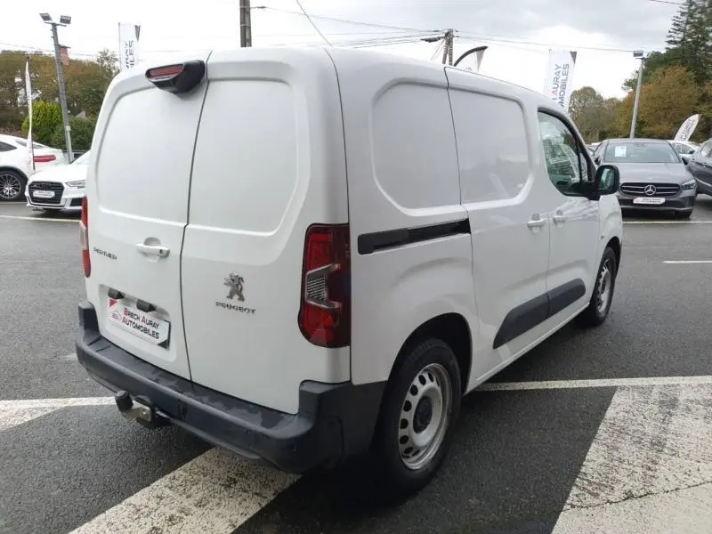 Vue 3/4 arrière droite d'un Peugeot Partner blanc avec portes battantes et crochet d'attelage visible.
