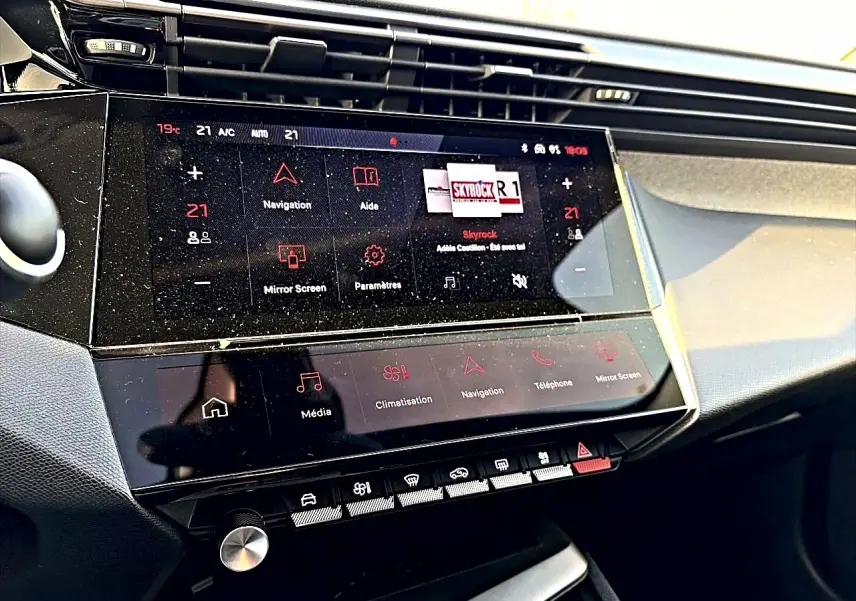 Vue rapprochée de la console centrale tactile du Peugeot 408 Hybrid 145 allure noir, affichant les commandes multimédia et climatisation.