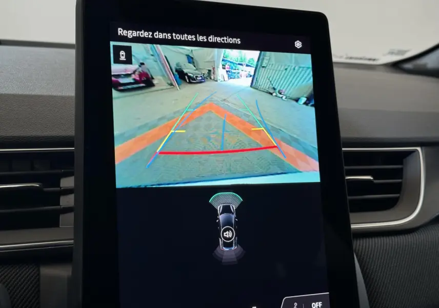 Écran tactile central du Renault Captur blanc 2025 montrant la caméra de recul avec lignes de guidage colorées.