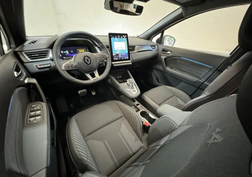Vue intérieure avant droite du Renault Captur esprit Alpine E-Tech 2025, avec tableau de bord numérique et écran tactile vertical.