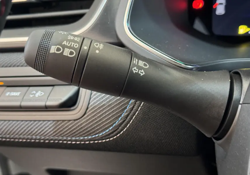 Gros plan sur la commande des phares et clignotants du tableau de bord intérieur du Renault Captur blanc esprit Alpine E-Tech.