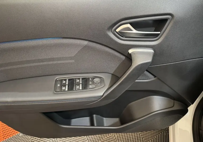 Gros plan sur la porte côté gauche du Renault Captur blanc 2025, avec commandes électriques et poignée intégrée.