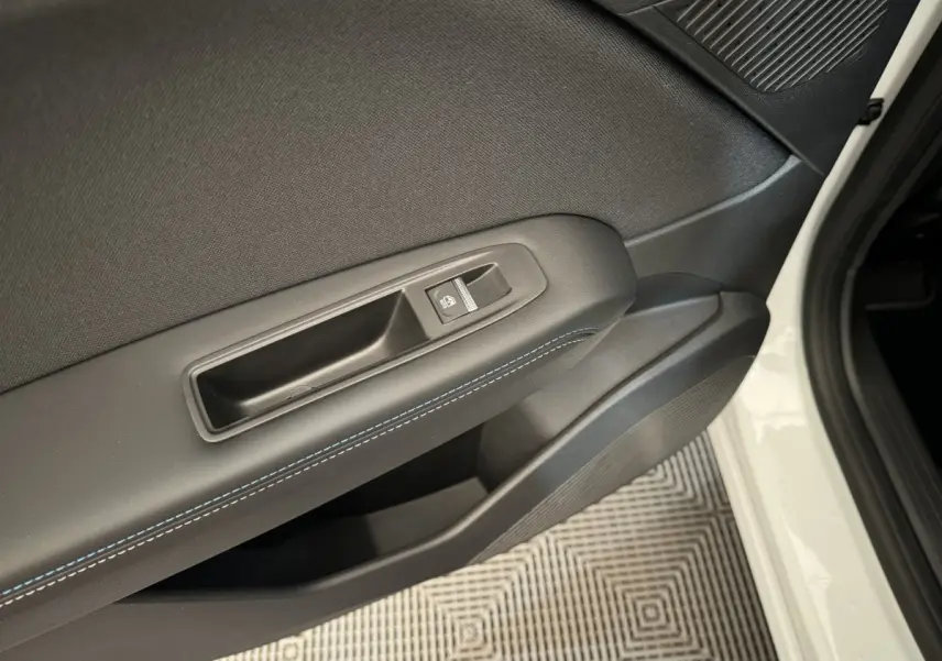 Gros plan sur la porte avant droite blanche du Renault Captur esprit Alpine, avec bouton de lève-vitre et surpiqûres bleues.