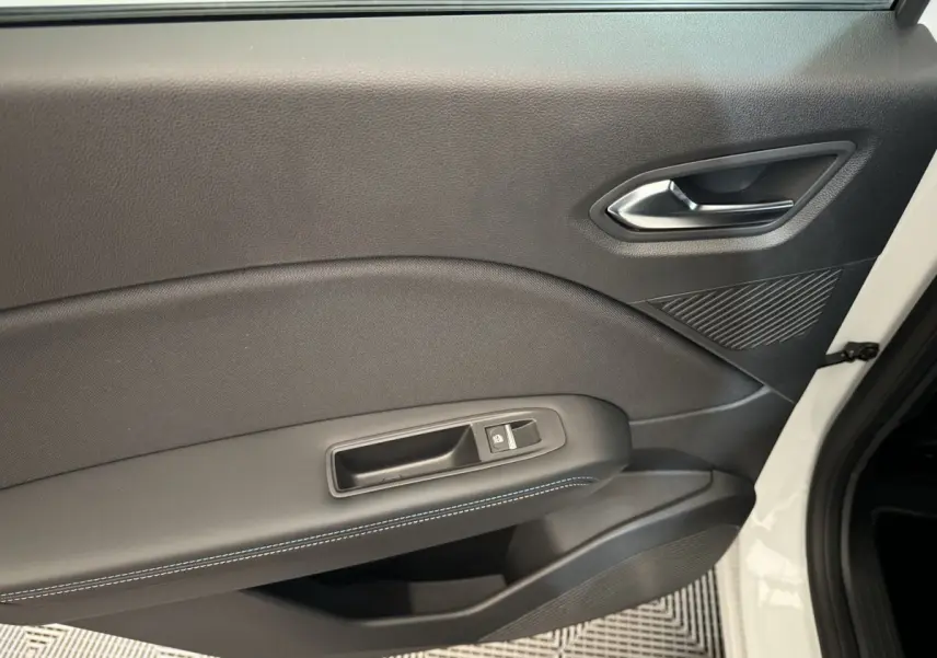 Gros plan sur la porte intérieure côté droit du Renault Captur blanc, avec couture bleue et bouton de verrouillage.