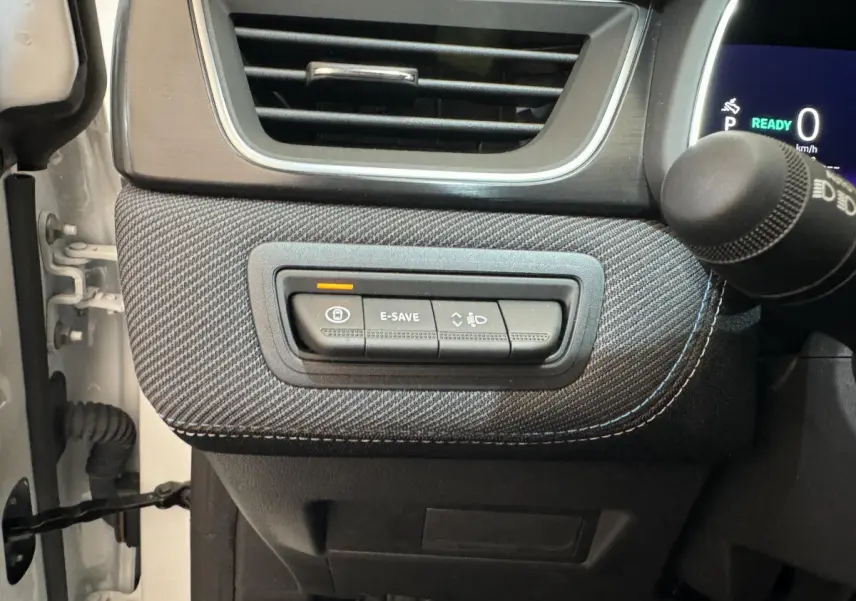 Gros plan sur les commandes à gauche du volant du Renault Captur blanc esprit Alpine E-Tech 2025, avec bouton E-SAVE allumé.