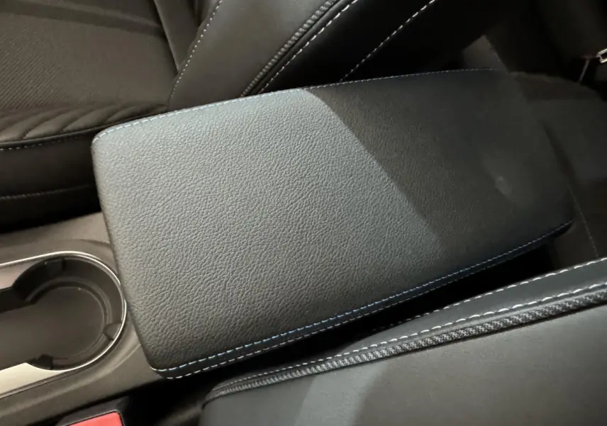 Accoudoir central noir avec surpiqûres bleues, vue rapprochée de l'intérieur du Renault Captur blanc esprit Alpine E-Tech.