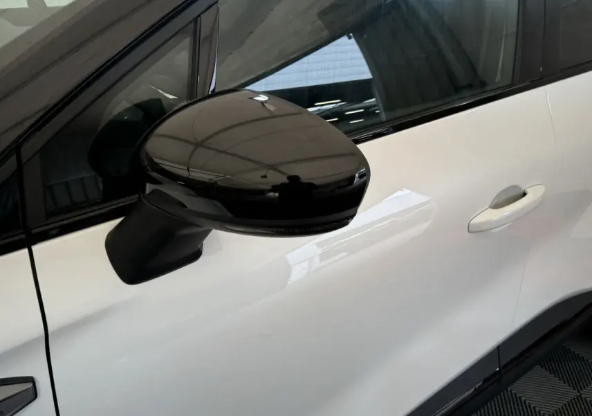 Rétroviseur noir en gros plan côté gauche sur la porte blanche d'un Renault Captur esprit Alpine E-Tech 2025.