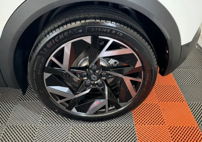 Gros plan sur la roue avant droite du Renault Captur blanc esprit Alpine E-Tech avec jante noire et argentée au design géométrique.