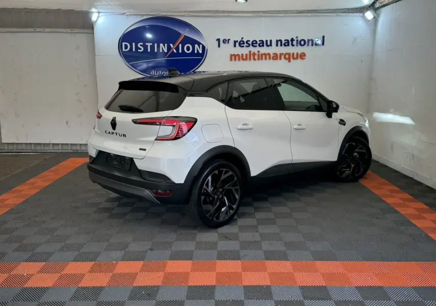 Vue 3/4 arrière droite du Renault Captur blanc esprit Alpine E-Tech avec toit noir et jantes noires en showroom.
