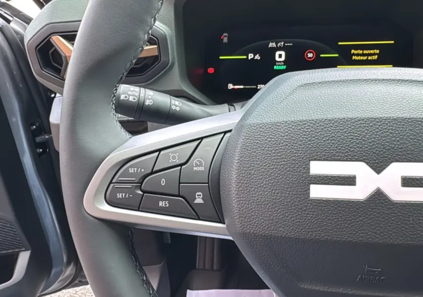 Gros plan sur le volant cuir gris du Dacia Bigster Hybrid 155 Extreme Plus avec commandes multifonctions et tableau de bord digital.