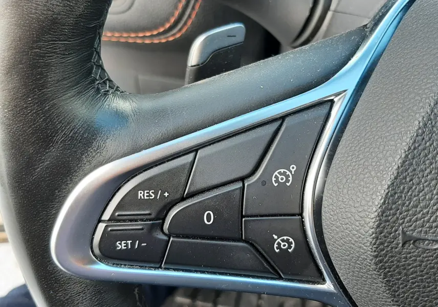 Gros plan sur les commandes de régulateur de vitesse au volant cuir noir du Renault Captur blanc toit noir 2020.