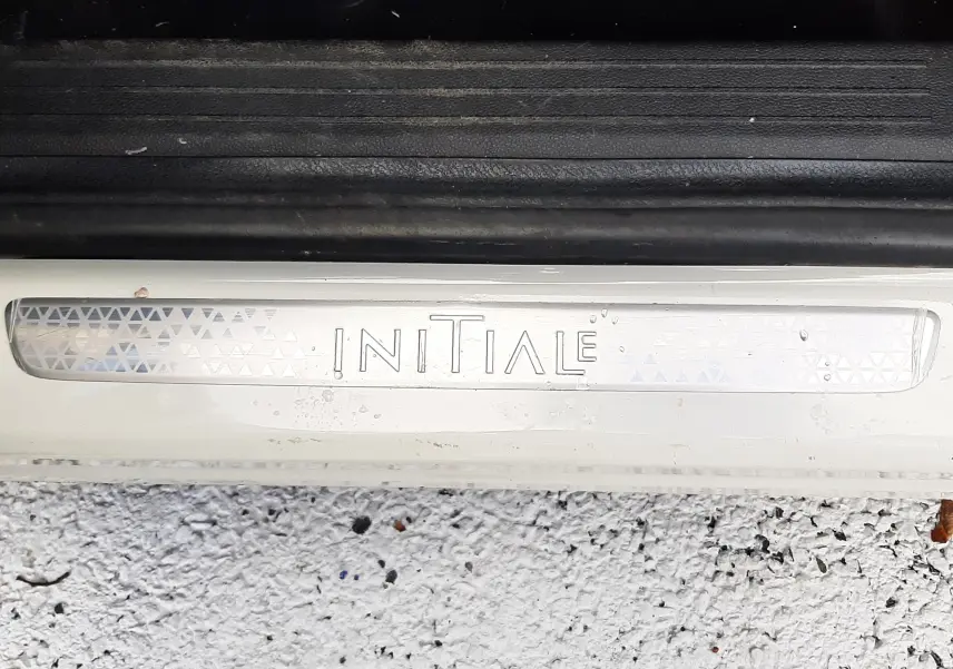 Gros plan sur la plaque de seuil de porte blanche avec inscription "INITIALE" du Renault Captur 2020 finition Initial Paris.