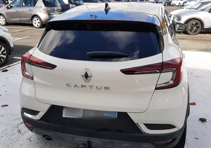 Vue arrière d'un Renault Captur blanc avec toit noir, montrant les feux LED et l'attelage de remorque.