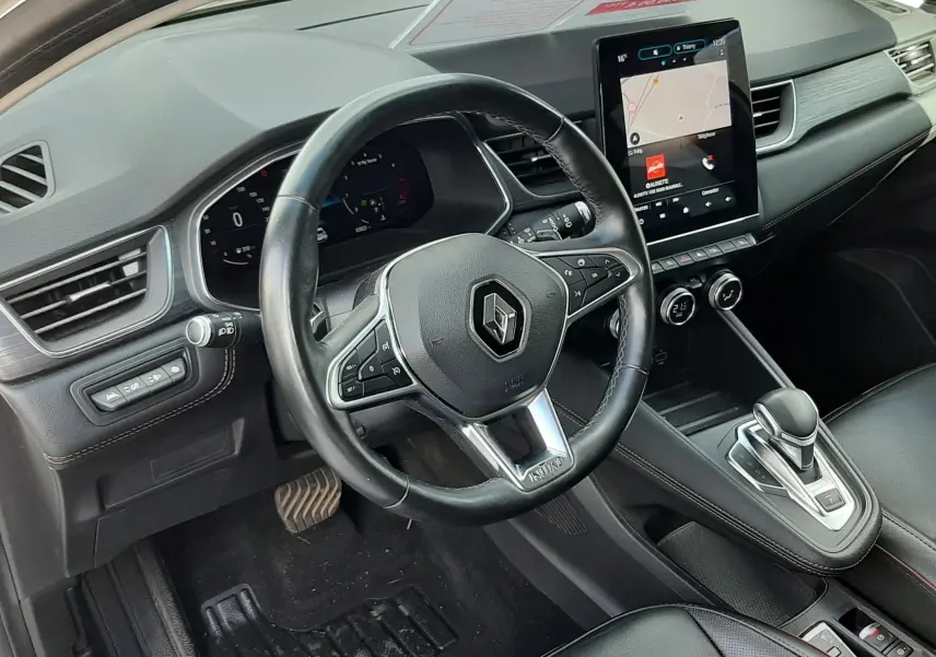 Vue intérieure côté conducteur du Renault Captur 2020, tableau de bord noir avec écran tactile vertical et volant cuir.