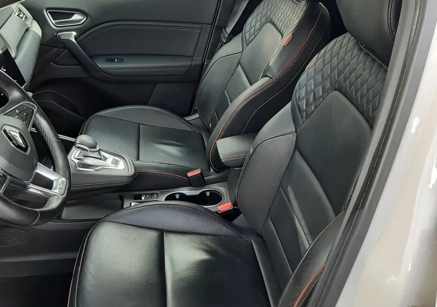 Vue intérieure côté conducteur du Renault Captur blanc toit noir 2020, sièges cuir noirs avec surpiqûres rouges et console centrale.