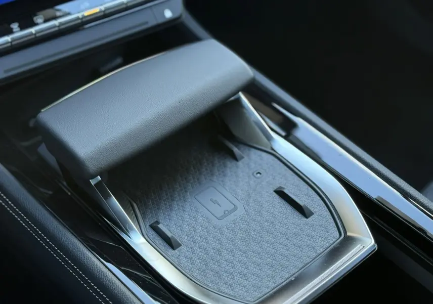 Détail de la console centrale noire du Renault Espace VI hybride avec chargeur smartphone à induction et accoudoir.