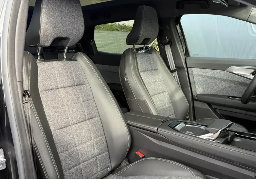Intérieur avant du Renault Espace VI hybride 2025, sièges tissu gris et cuir noir avec accoudoir central et porte ouverte côté gauche.