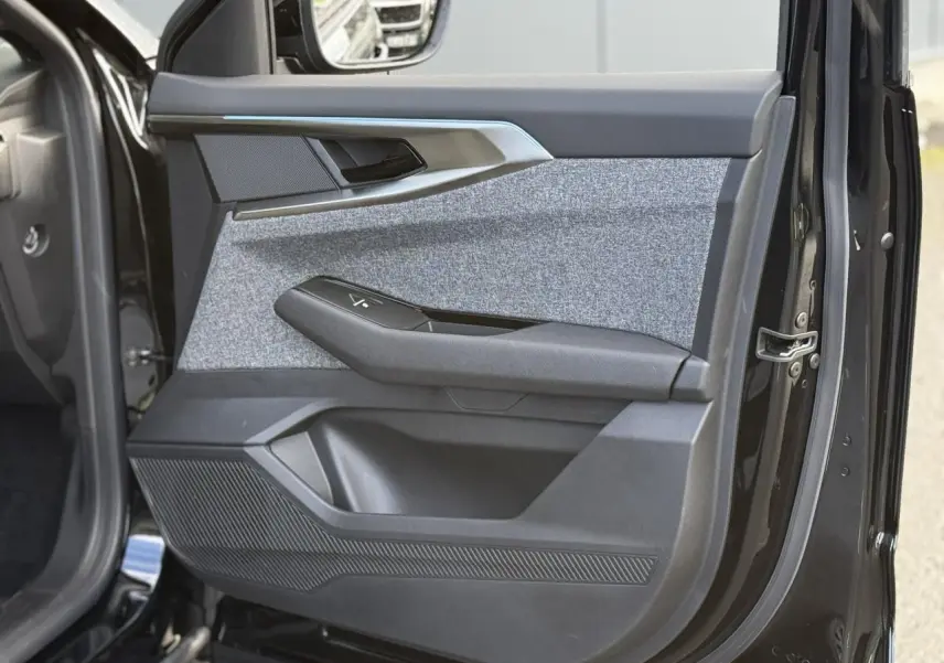 Gros plan sur la porte avant gauche du Renault Espace VI noir étoilé, avec habillage tissu gris et commandes électriques.