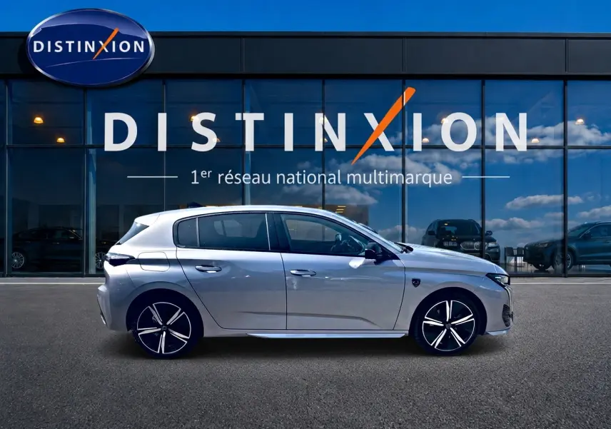 Peugeot 308 gris vue de profil côté gauche, avec jantes alu distinctives, devant une vitrine Distinxion.