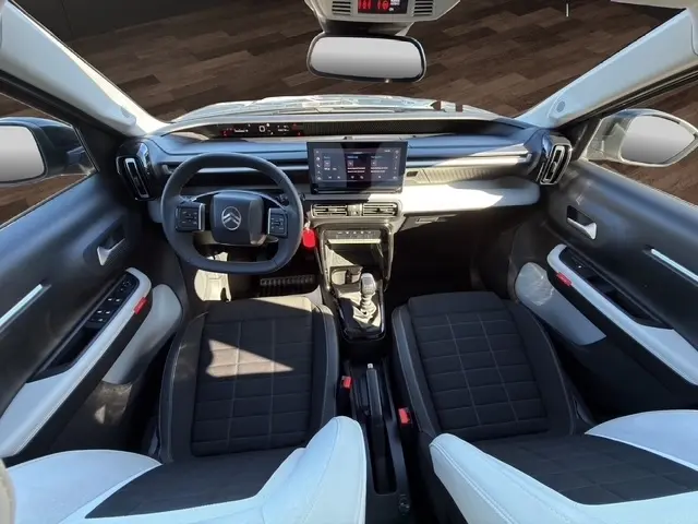 Vue intérieure avant de la Citroën C3 Turbo 100 BVM6 MAX 2025, tableau de bord noir avec écran tactile central et sièges bicolores.