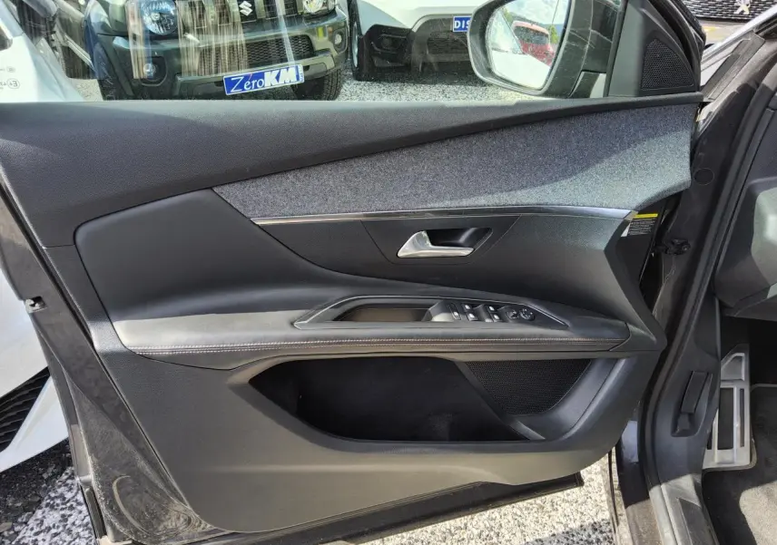 Gros plan sur la porte avant gauche intérieure du Peugeot 3008 gris métallisé, avec commandes électriques et garniture tissu et cuir.