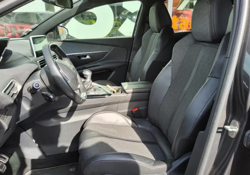 Vue intérieure côté conducteur du Peugeot 3008 GT Line 2017, sièges TEP et tissu noirs avec volant cuir perforé.