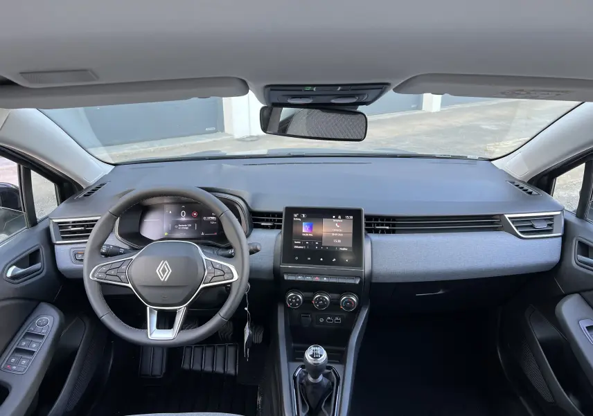 Vue intérieure frontale du tableau de bord et volant de la Renault Clio V gris schiste avec écran tactile 7 pouces et boîte manuelle.