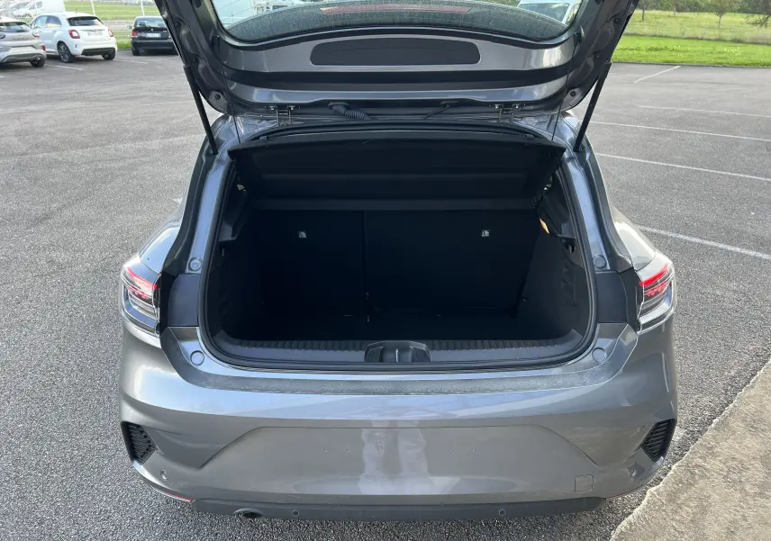 Coffre ouvert vu de l'arrière d'une Renault Clio V gris schiste avec feux arrière LED et protections chromées.