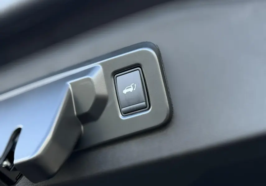 Bouton d'ouverture électrique du hayon sur le panneau intérieur d'un Renault Espace VI noir étoilé.