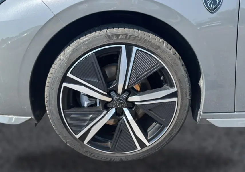 Gros plan sur la roue avant droite d’une Peugeot 308 gris 2025, avec jante alu au design moderne et logo lion.