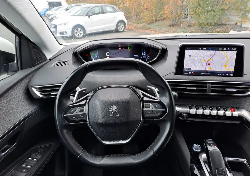 Vue intérieure du tableau de bord et volant noir du Peugeot 3008 blanc, avec écran tactile et commandes modernes visibles.