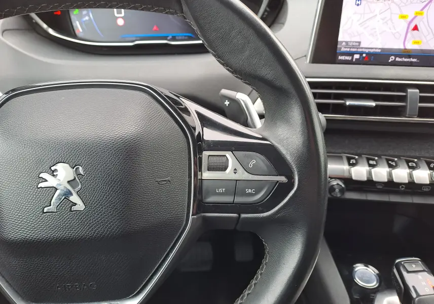 Gros plan sur le volant cuir noir du Peugeot 3008 2018 avec commandes intégrées et écran GPS en arrière-plan.