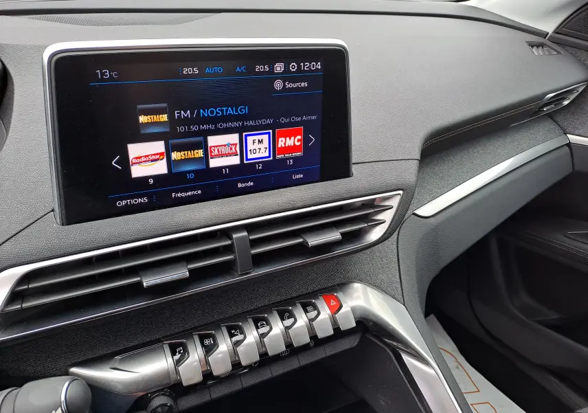 Vue rapprochée de la console centrale du Peugeot 3008 blanc, avec écran tactile et commandes piano en aluminium.