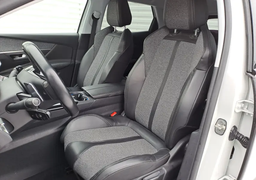 Vue intérieure côté conducteur du Peugeot 3008 blanc 2018, sièges bi-matière cuir et tissu gris avec volant noir.