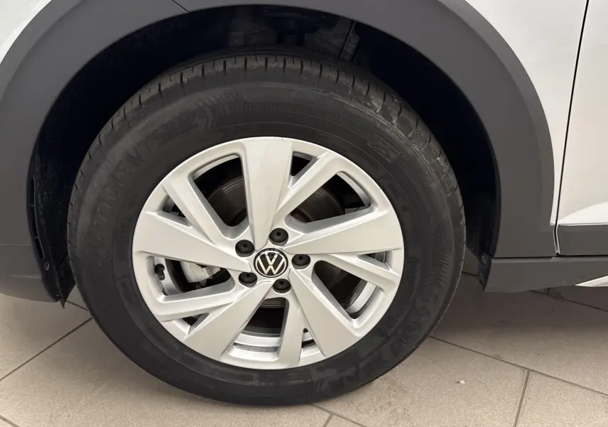 Gros plan sur la roue avant gauche du Volkswagen Taigo gris cendré, mettant en valeur la jante alliage et le logo VW central.