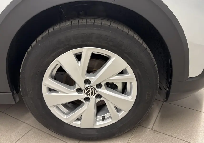 Gros plan sur la roue avant droite d'un Volkswagen Taigo gris cendré avec jante alliage à cinq branches.