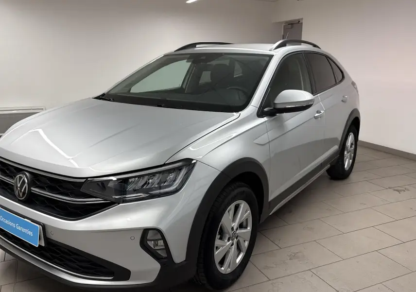 Volkswagen Taigo gris cendré en 3/4 avant droit, avec calandre noire et jantes alliage visibles.