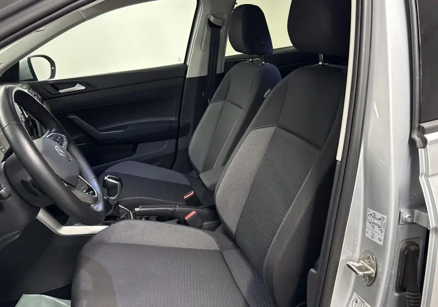 Vue intérieure côté conducteur du Volkswagen Taigo 2024 gris cendré, montrant les sièges avant et le volant.