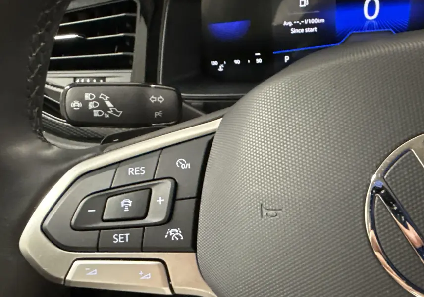 Gros plan sur le volant du Volkswagen Taigo 2024 avec commandes intégrées et tableau de bord numérique en arrière-plan.