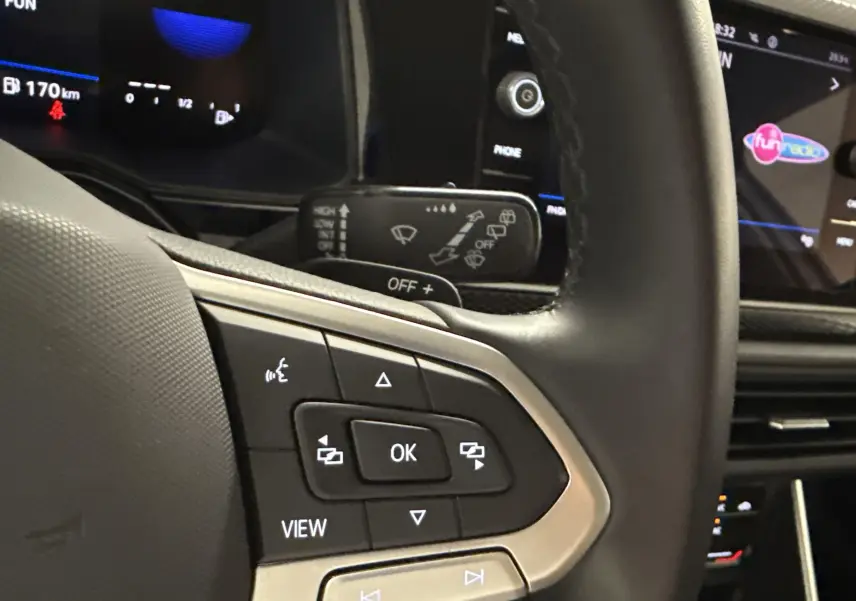 Gros plan sur le volant et le tableau de bord numérique du Volkswagen Taigo gris cendré, version 2024 avec commandes intégrées.