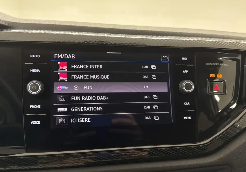 Écran tactile central du Volkswagen Taigo 2024 affichant les stations radio FM/DAB avec finition intérieure noire texturée.