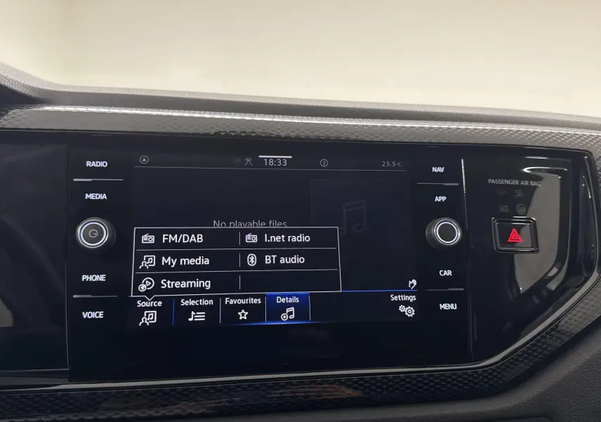 Écran tactile central du Volkswagen Taigo 2024 affichant les options radio et streaming, entouré de commandes noires brillantes.