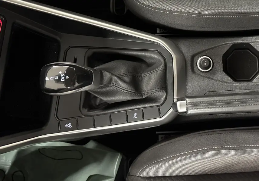 Vue plongeante sur la console centrale du Volkswagen Taigo 2024 avec levier de vitesse automatique et frein à main cuir noir.