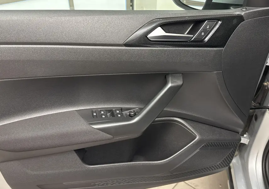 Vue rapprochée de la porte avant gauche du Volkswagen Taigo gris cendré avec commandes de vitres et verrouillage.