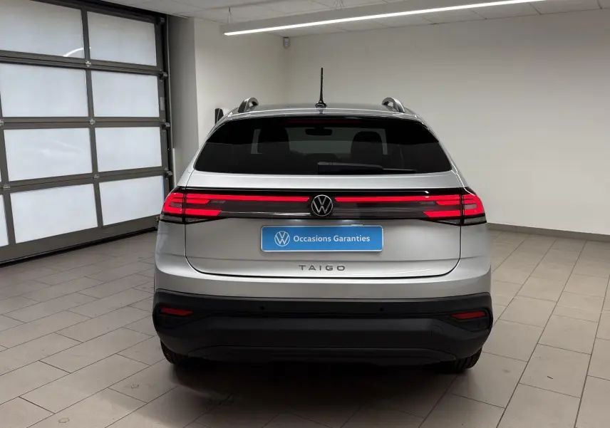 Vue arrière du Volkswagen Taigo gris cendré 2024 avec feux LED allumés dans un garage lumineux.
