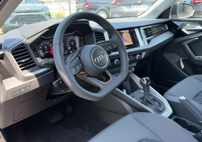 Vue intérieure côté conducteur de l'Audi A1 Sportback 2026 avec volant cuir multifonction et tableau de bord digital.