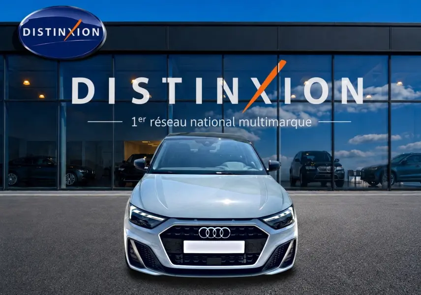 Audi A1 Sportback gris arrow vue de face, avec calandre noire et logo Audi bien visible devant un showroom Distinxion.