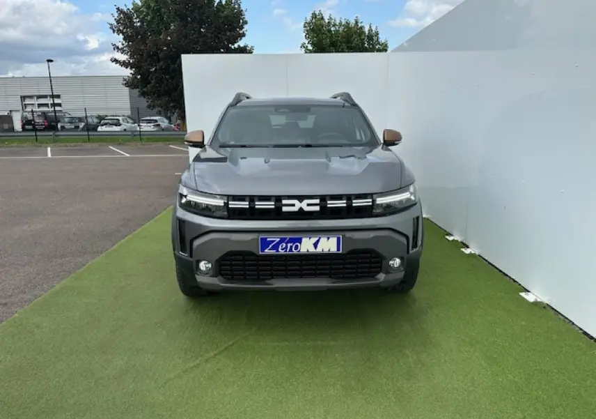 Vue frontale du Dacia Duster III gris schiste métal, avec calandre noire et phares LED étirés.