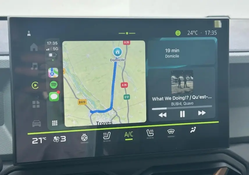 Écran tactile central du Dacia Duster III gris schiste, affichant navigation et musique en intérieur jour.
